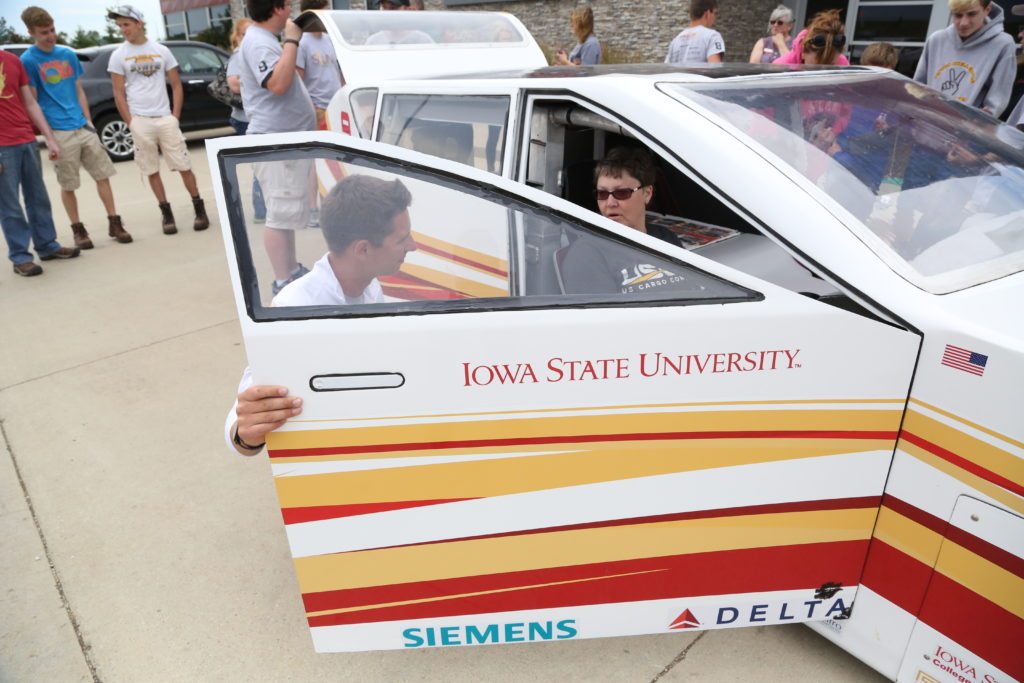 Sharyl sits in the solar car and learns more about the construction from an ISU student.