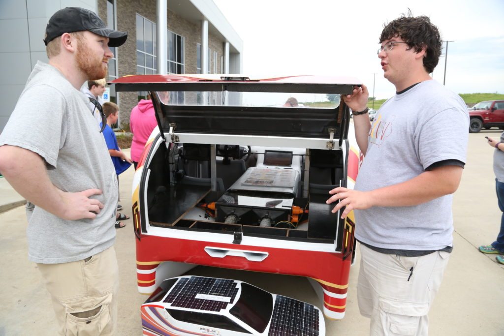 Todd listens as an ISU student explains how the solar car operates.