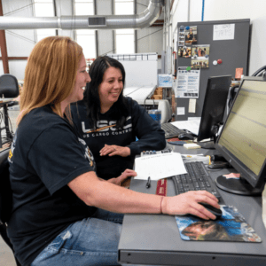 Jamie Noe working with another manufacturing team member at a computer.