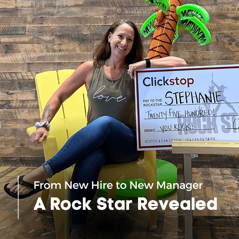 Employee, Stephanie Pierce, sitting in a yellow chair holding her large check after being crowned the Q2 Rock Star award winner.